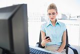 Focused businesswoman wearing glasses text messaging