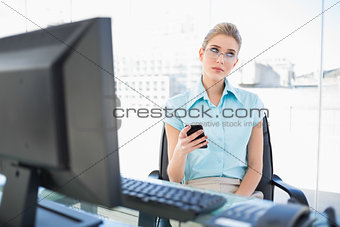 Pensive businesswoman wearing glasses text messaging