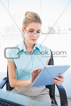 Focused businesswoman wearing glasses using tablet