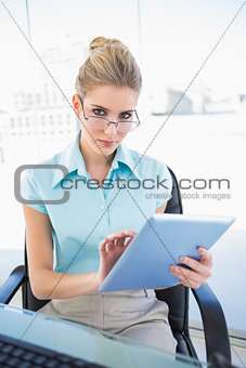 Serious businesswoman wearing glasses using tablet