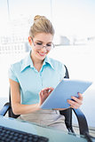 Cheerful businesswoman wearing glasses using tablet
