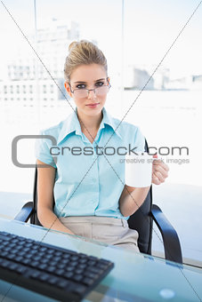 Serious businesswoman wearing glasses holding coffee
