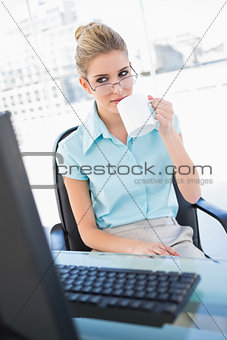 Relaxed businesswoman wearing glasses drinking coffee