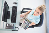Overhead view of serious businesswoman showing calculator