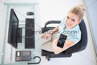 Overhead view of smiling businesswoman showing smartphone