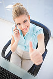 High angle view of smiling businesswoman on the phone giving thumb up
