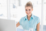 Smiling well dressed businesswoman using laptop