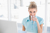 Smiling well dressed businesswoman drinking water