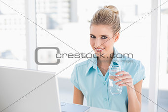Smiling well dressed businesswoman holding water