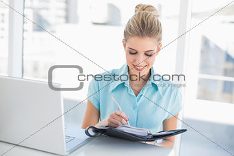 Smiling well dressed businesswoman writing on datebook