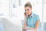 Relaxed smart businesswoman on the phone while using laptop