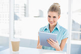 Cheerful classy woman using tablet while having a break