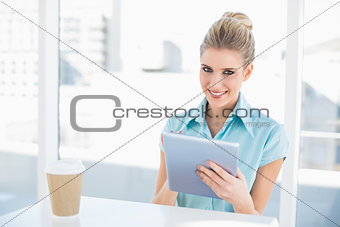 Cheerful classy woman using tablet while having a break