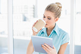 Peaceful classy woman using tablet while drinking coffee