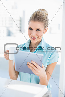 Smiling elegant woman using tablet holding coffee