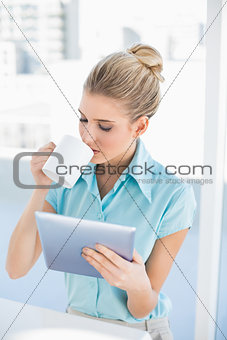 Relaxed elegant woman using tablet while drinking coffee