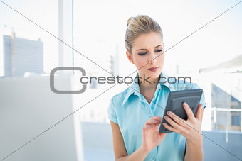 Frowning elegant woman using calculator