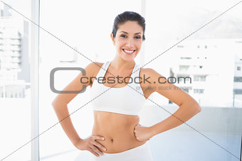 Fit happy woman in sportswear with hands on hips