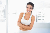 Fit laughing woman in sportswear with arms crossed looking at camera