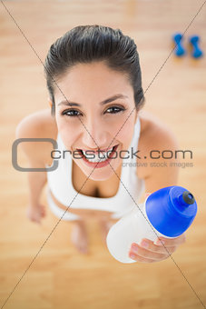 Fit smiling woman holding sports bottle