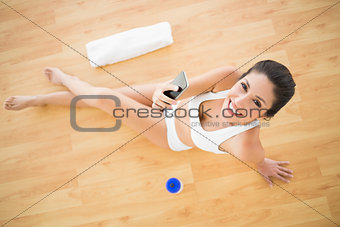 Fit happy woman sending a text during her workout looking at camera