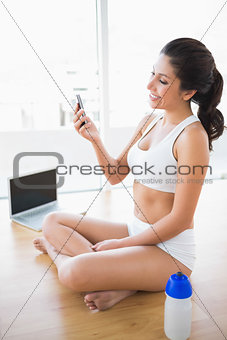 Fit woman sending a text with smartphone