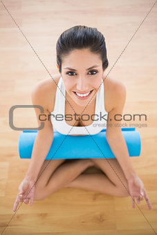 Pretty woman with her exercise mat sitting in lotus pose