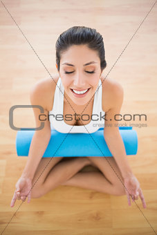 Calm woman with her exercise mat sitting in lotus pose