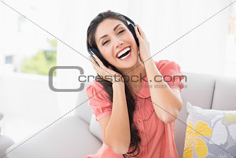 Pretty brunette sitting on her sofa listening to music