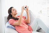 Brunette sitting on her sofa taking a picture
