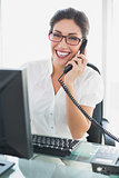 Smiling businesswoman sitting at her desk talking on the phone