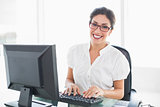 Cheerful businesswoman working at her desk looking at camera