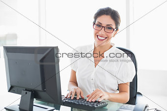 Cheerful businesswoman working at her desk looking at camera