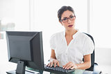Serious businesswoman working at her desk looking at camera