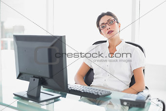 Frowning businesswoman sitting at her desk looking at computer