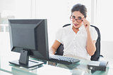 Happy businesswoman sitting at her desk looking at camera