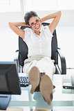 Relaxed businesswoman sitting at her desk with her feet up looking at camera