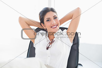Reclining businesswoman sitting at her desk smiling at camera
