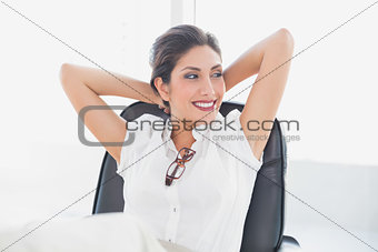Reclining businesswoman sitting at her desk smiling