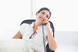 Reclining businesswoman sitting at her desk talking on phone