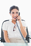 Happy businesswoman sitting at her desk on the phone