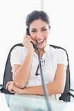 Laughing businesswoman sitting at her desk on the phone