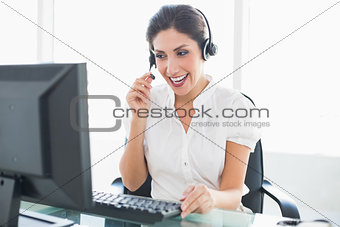 Laughing call centre agent sitting at her desk on a call