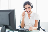 Happy call centre agent sitting at her desk on a call
