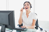 Cheerful call centre agent sitting at her desk on a call