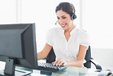 Cheerful call centre agent working at her desk on a call