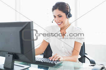 Cheerful call centre agent working at her desk on a call