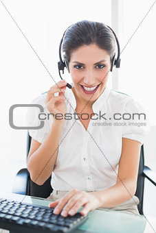 Smiling call centre agent working at her desk on a call