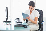 Smiling businesswoman using her digital tablet at desk