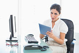 Stern businesswoman using her digital tablet at desk